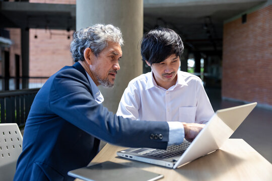 Asian senior professor is giving advice  to the college student on the research thesis while sitting in the university faculty for education, academic and business