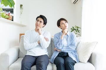 自宅のソファに座り考えるカップル