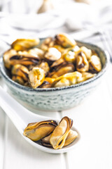Shelled mussels meat in ceramic spoon on white table