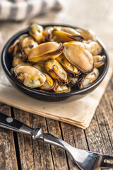 Shelled mussels meat in bowl on wooden table.
