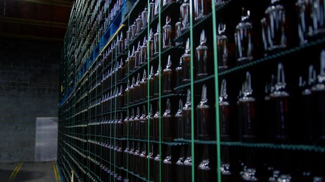 Slow motion reveal and move along a huge store of bottles in a factory