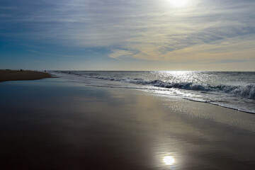 Vagues et écume sur une plage au bord de l'océan avec un ciel dégagé et vue sur l'horizon