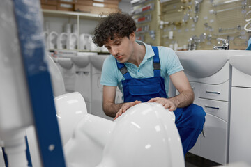 Plumber choosing new ceramic lavatory bowl at plumbing shop
