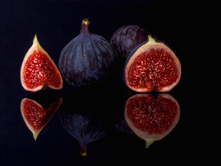 figs a group of fruits cut in half, rich in valuable minerals and nutrients, black background reflected in the base, warm colors, inside of a fig fruit for health