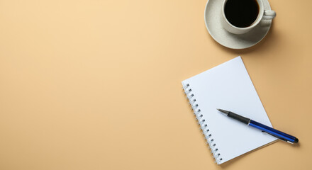 Open notebook with pen and cup of coffee on tan surface
