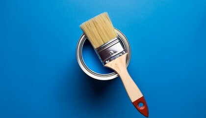 can of blue paint with brush on blue background top view