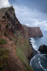 Very steep and tall cliff towering above coast with some rough Atlantic waters, Madeira, Portugal