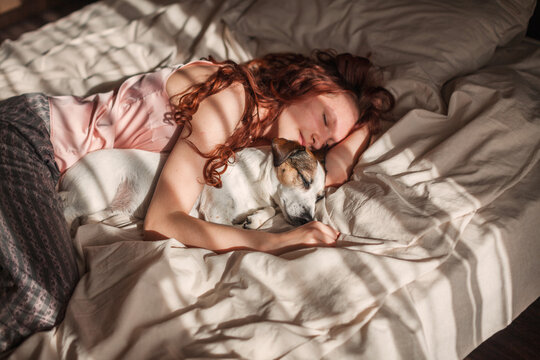 Young woman sleeping with dog on bed