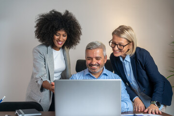 Business meeting. Businesspeople laughing while working at an office table. three business people...