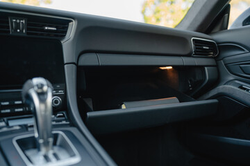 Glove compartment of a luxury car with a sleek handle on a minimalist dashboard.
