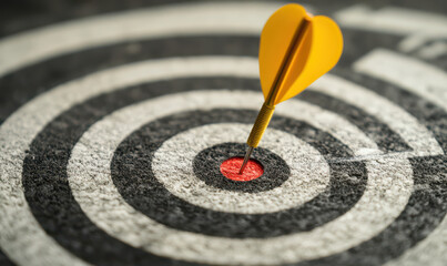 yellow dart hitting center of dartboard. red bullseye is in focus, representing success and accuracy