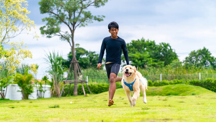 Happy Asian man playing ball with Golden Retriever dog breed at pets friendly dog park. Domestic dog with owner enjoy outdoor active lifestyle on summer holiday vacation. Pet humanization concept.