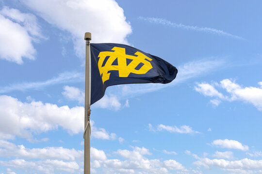 Notre Dame, IN, USA - October 25, 2024: A blue and yellow University of Notre Dame flag flying on top of the Notre Dame Stadium on campus with a blue sky in the background.