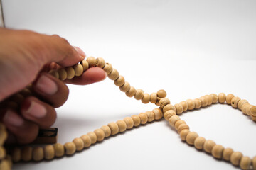 Male hand asian holding muslim beads rosery or tasbih for pray with isolated background.