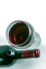 Glass and bottle of red wine on a white background.