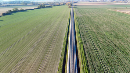 Aerial View of Railway Tracks Stretching Across Expansive Green Agricultural Fields