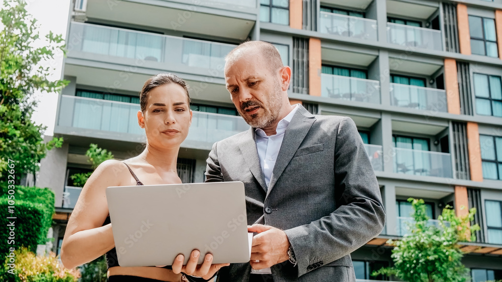 Wall mural a businessman and a young female assistant discuss a new project outdoors while using a laptop. thei