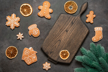 Christmas culinary background with gingerbread cookies and empty wooden board, fir branch and dried orange slices, top view, flat lay.