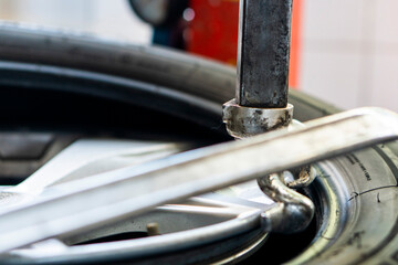 Mechanic works in tire repair shop. Car service mechanic puts wheel on car rim using special...