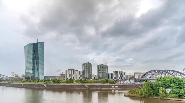 Frankfurt skyline featuring the modern ECB headquarters skyscraper with reflective steel-glass facade, train arch bridge and rainy clouds in the sky timelapse. Frankfurt am Main, Germany