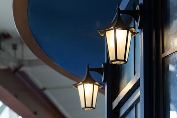 Two street lamps are lit up against a blue ceiling.