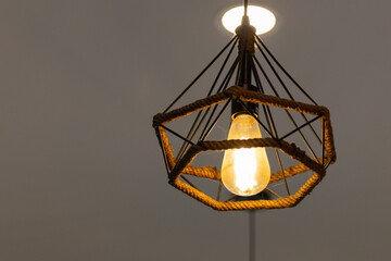 A vintage light bulb hanging from a rope in a room