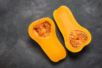 Halves of raw Butternut pumpkin on dark grunge background, top view, flat lay, copy space