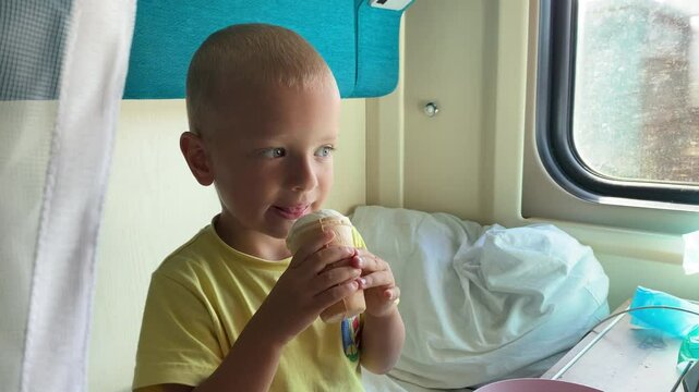 Family traveling on passenger train. Child licks ice cream in train compartment.