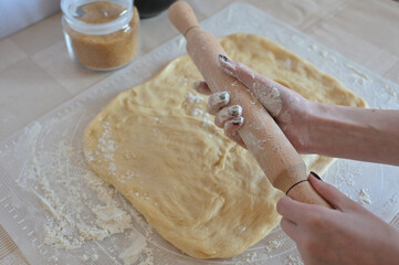 Baking ingredients for baking sweet buns,  a woman puts flour on a rolling pin with her hands,...