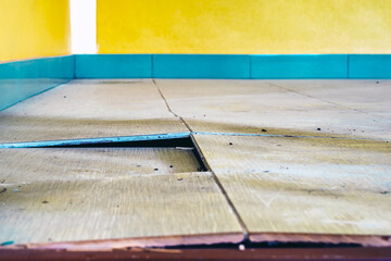 Background with falling off tiled tiles in living room. Close up of cracked ceramic tiles on a...