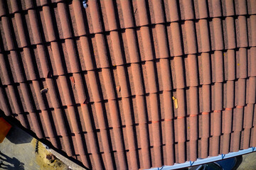 Aerial view of a tiled roof after partial repairs, showcasing replaced tiles and an inspection following the renovation. Drone photography captures the roof from above.
