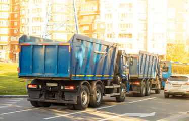 Naklejka premium Two large trucks with blue bodies drive along a city street