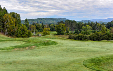 A green golf course among the rolling hills with a cloudy sky on a beautiful summer day in Canada
