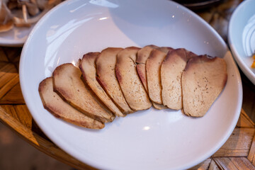 A close-up shot of various types of mushrooms and tofu slices arranged on white ceramic plates,...
