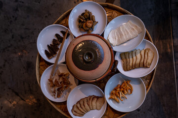 A close-up shot of various types of mushrooms and tofu slices arranged on white ceramic plates,...