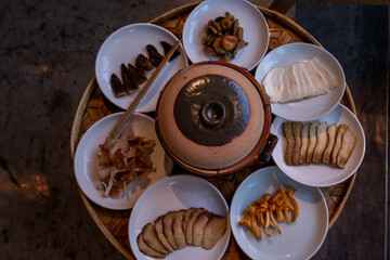 A close-up shot of various types of mushrooms and tofu slices arranged on white ceramic plates,...