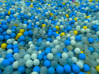 A colorful ball pit filled with blue, white, yellow, and transparent balls creates an inviting and vibrant play space. The mix of colors adds an energetic yet visually soothing effect.