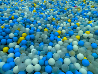 A colorful ball pit filled with blue, white, yellow, and transparent balls creates an inviting and vibrant play space. The mix of colors adds an energetic yet visually soothing effect.