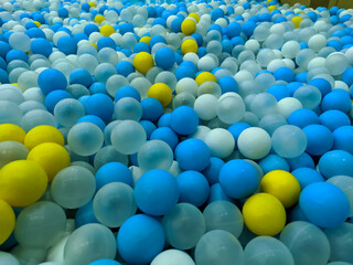 A colorful ball pit filled with blue, white, yellow, and transparent balls creates an inviting and vibrant play space. The mix of colors adds an energetic yet visually soothing effect.