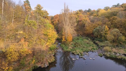 Autumn colors reflecting on a calm river surrounded by lush trees in a tranquil natural setting