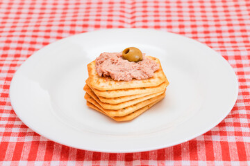 Crispy Salted Cracker with Liver Pate and Olives on White Plate. Easy Snack