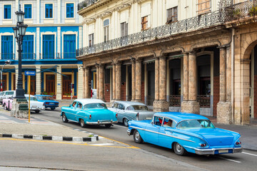 american classic cars on the street of the havana, cuba in front of historic buildings