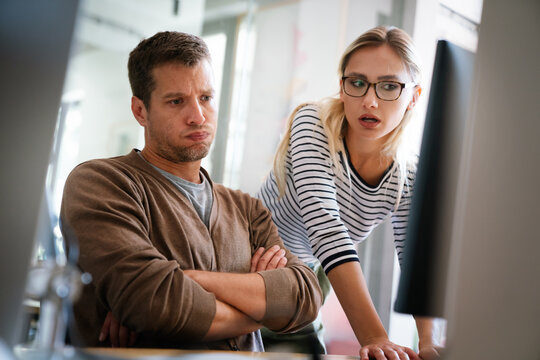 Upset businesspeople trying to work on line with a desktop computer looking at monitor at office