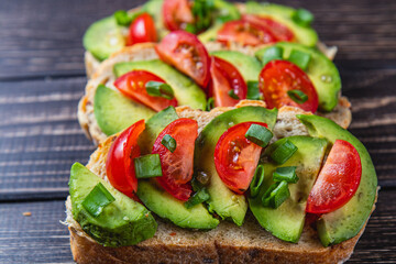 Avocado toast topped with tomato and green onion on a slice of carrot bread