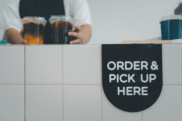 Order and pick up here sign on the counter bar with barista put two iced coffees at the coffee shop