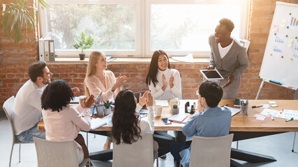 Black guy with digital tablet making report during business meeting in modern office