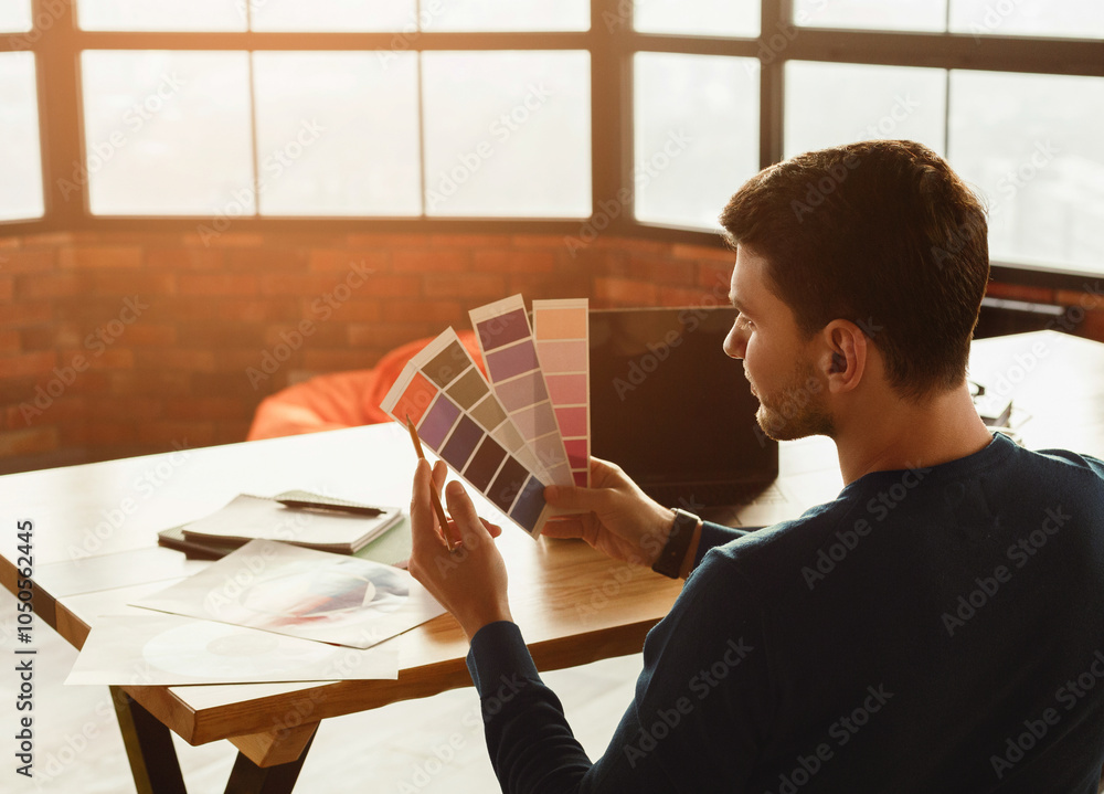 Poster unrecognizable designer guy working with color samples sitting in office. free space, selective focu