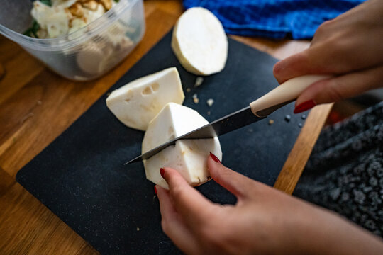 Woman cutting celery root in domestic kitchen. Preparing vegetables for soup. Top view.