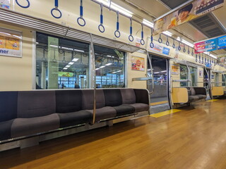 Osaka, Japan - 01.01.2024: Interior of a women-only carriage of Nankai Railway train with empty seats, hanging handrails, windows, and advertisement when stopped at Namba Station (Nankai)