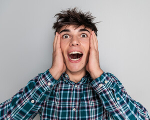 shocked casual guy covering face with palms and opening mouth